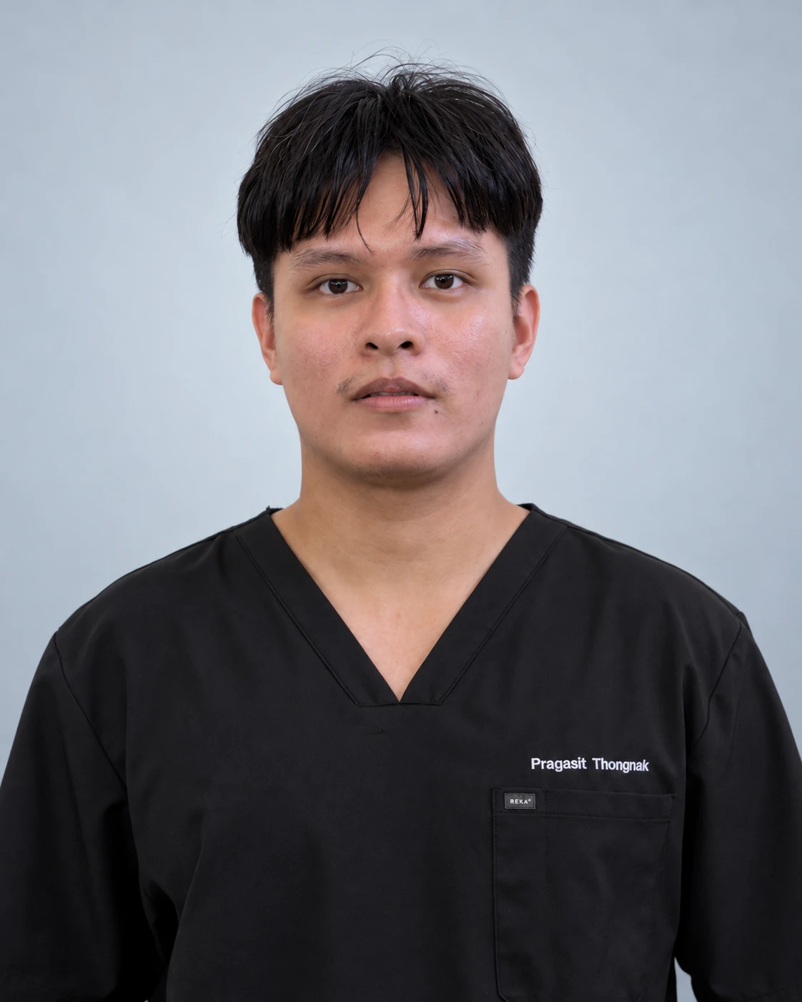 Pragasit (Dunk) Thongnak wearing black scrubs against a light neutral background.