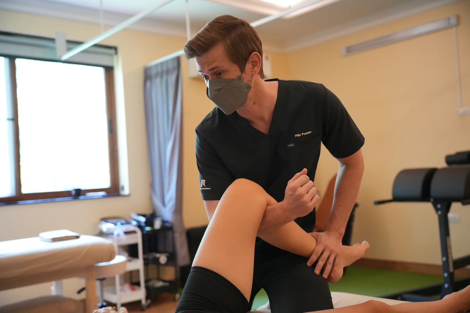 Felix guiding a hip movement assessment in the treatment room.