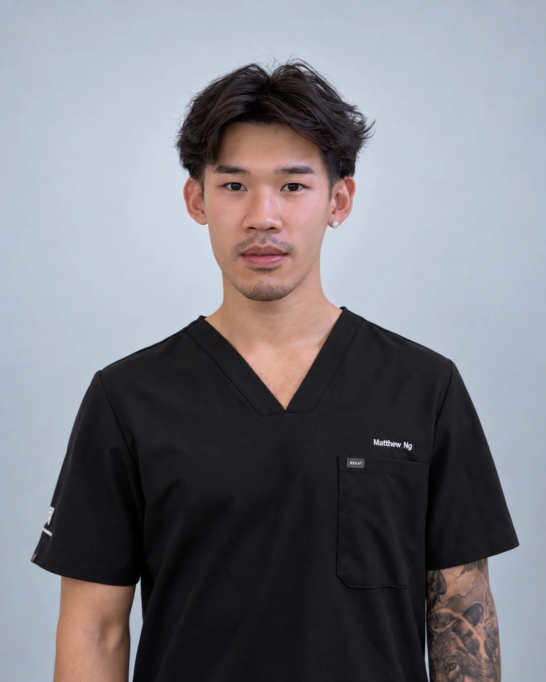 Matthew Vongsaphat Ngamtrakulchol wearing black scrubs against a light neutral background.